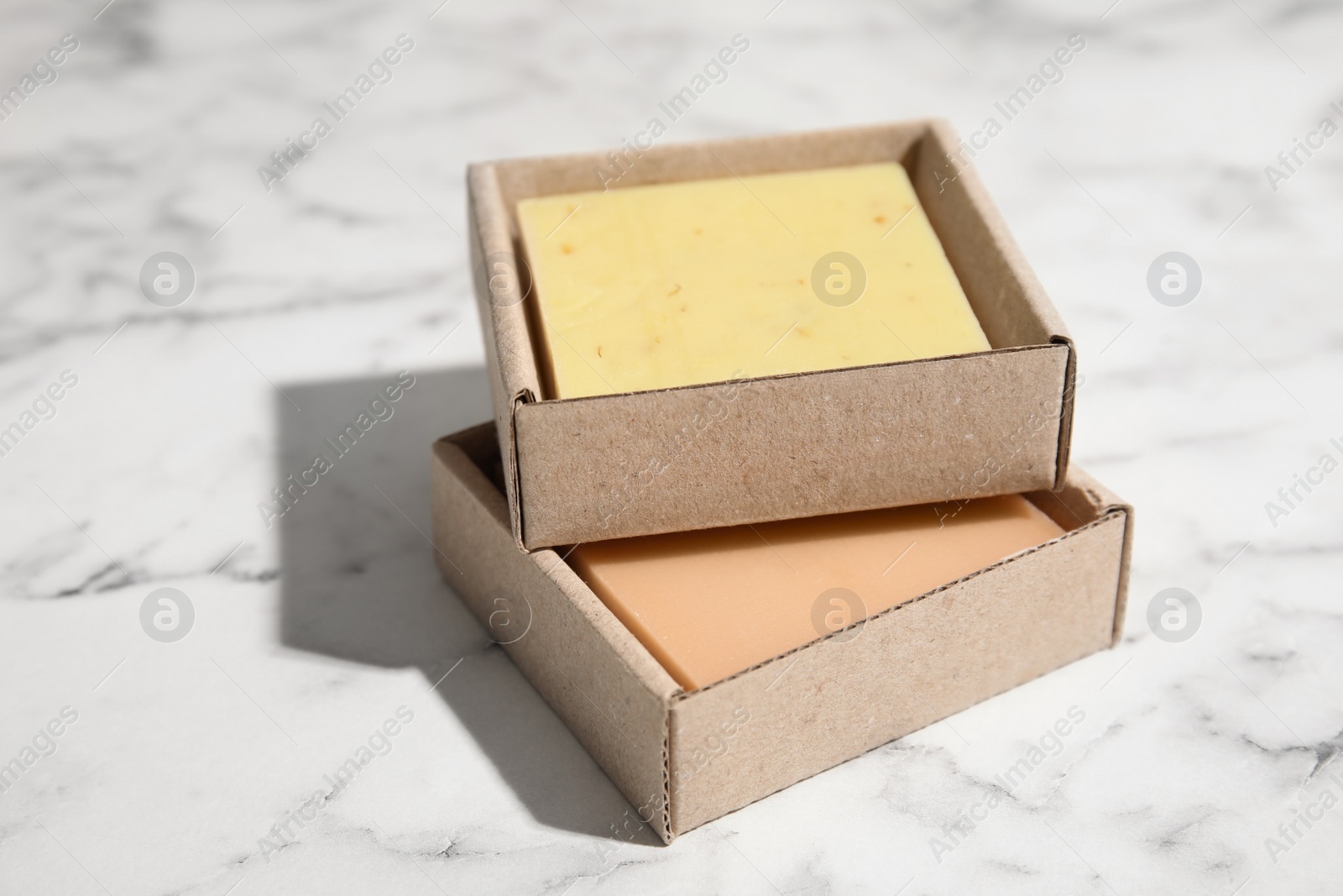 Photo of Hand made soap bars in cardboard packages on marble background