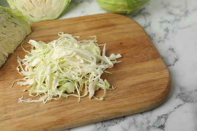 Photo of Chopped ripe cabbage on white marble table, closeup