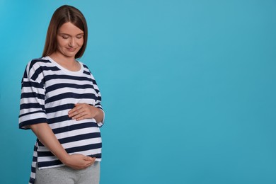 Photo of Happy young pregnant woman on light blue background. Space for text