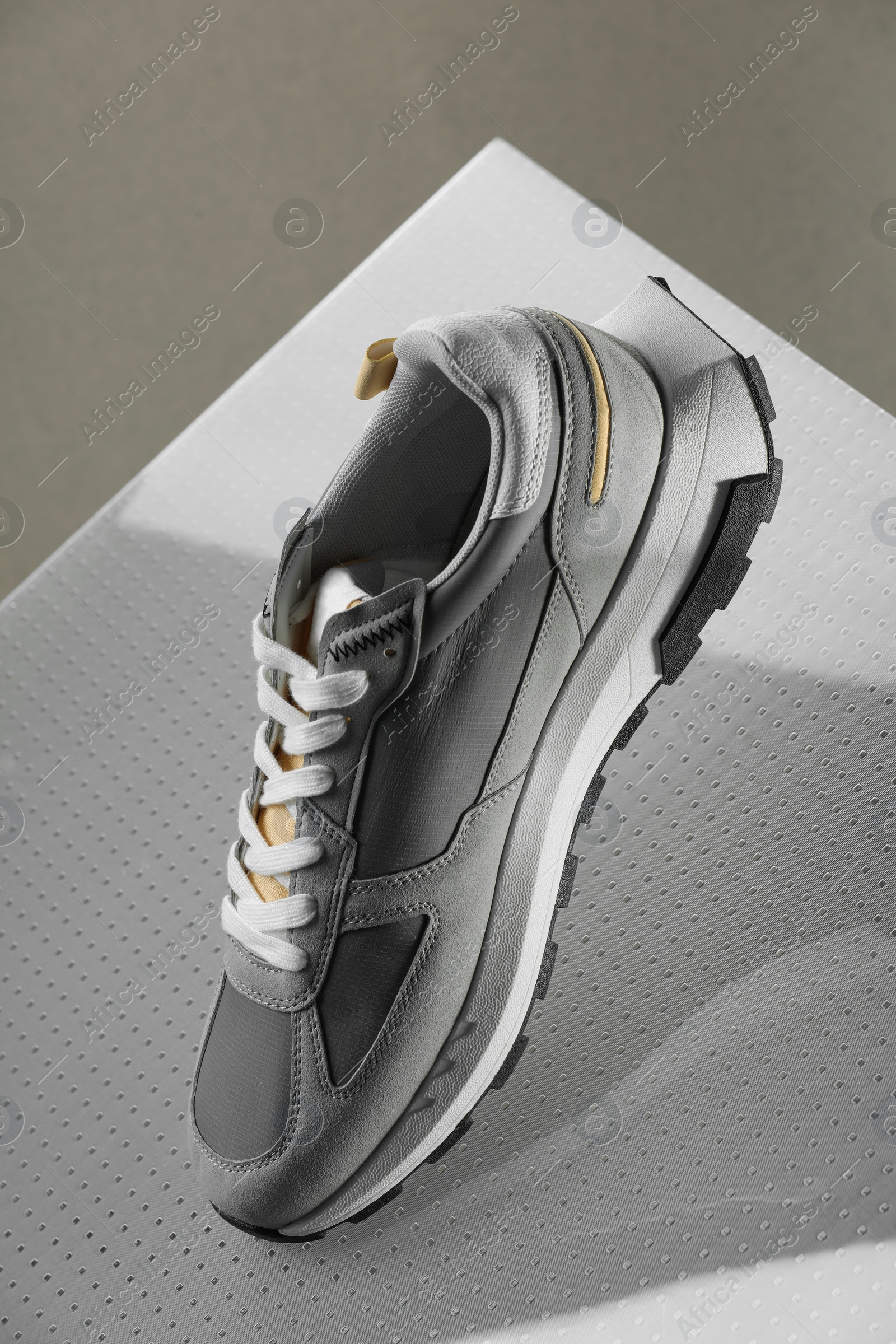 Photo of Stylish presentation of trendy sneaker against grey background