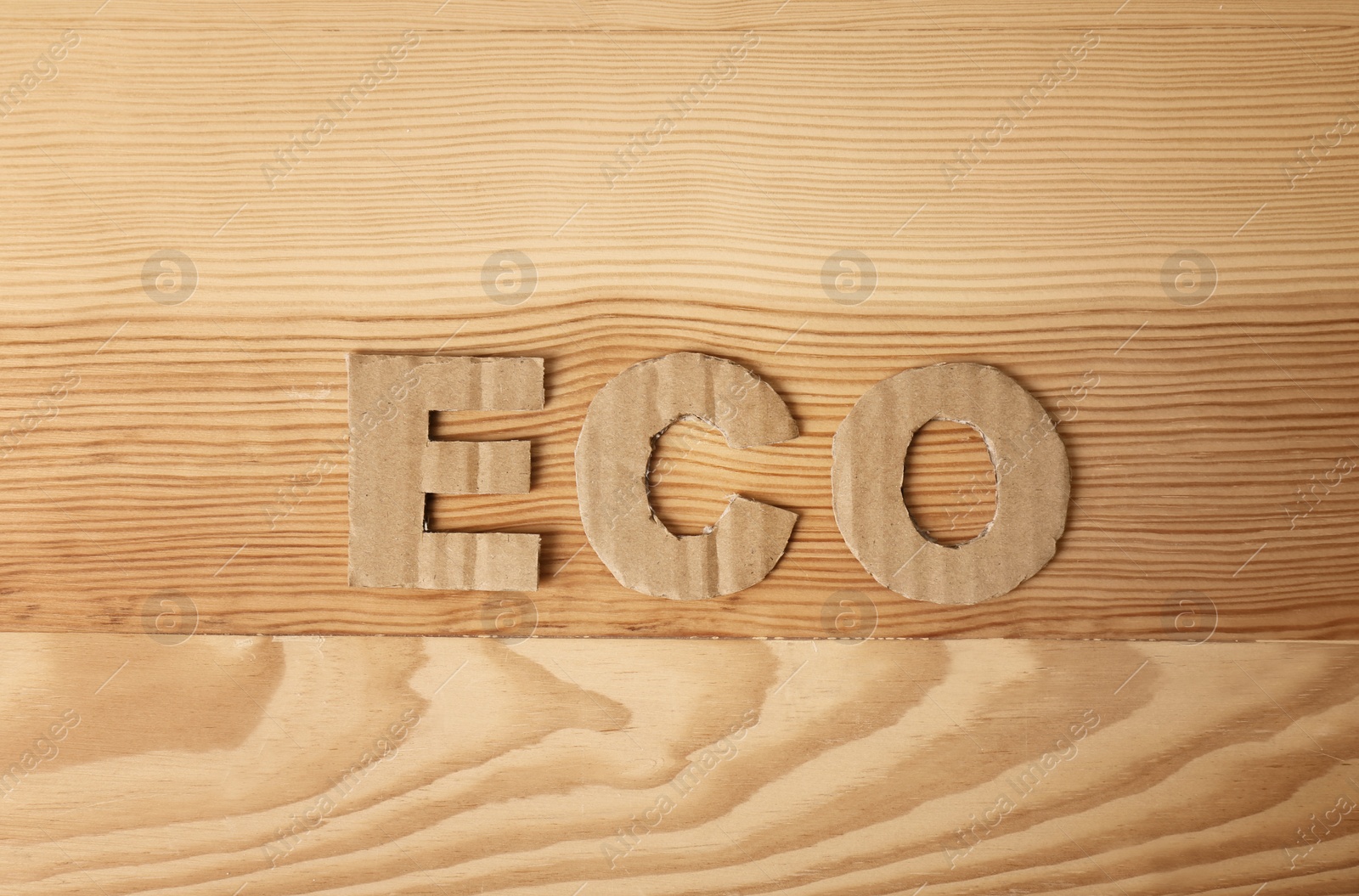 Photo of Word "Eco" made of cardboard letters on wooden background, top view