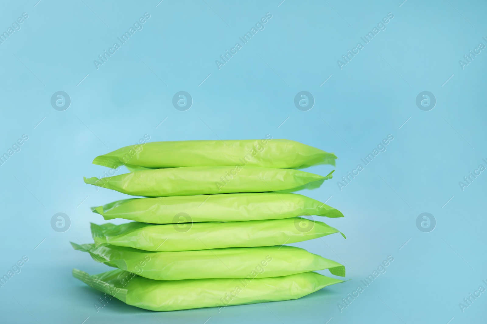 Photo of Stack of menstrual pads on light blue background