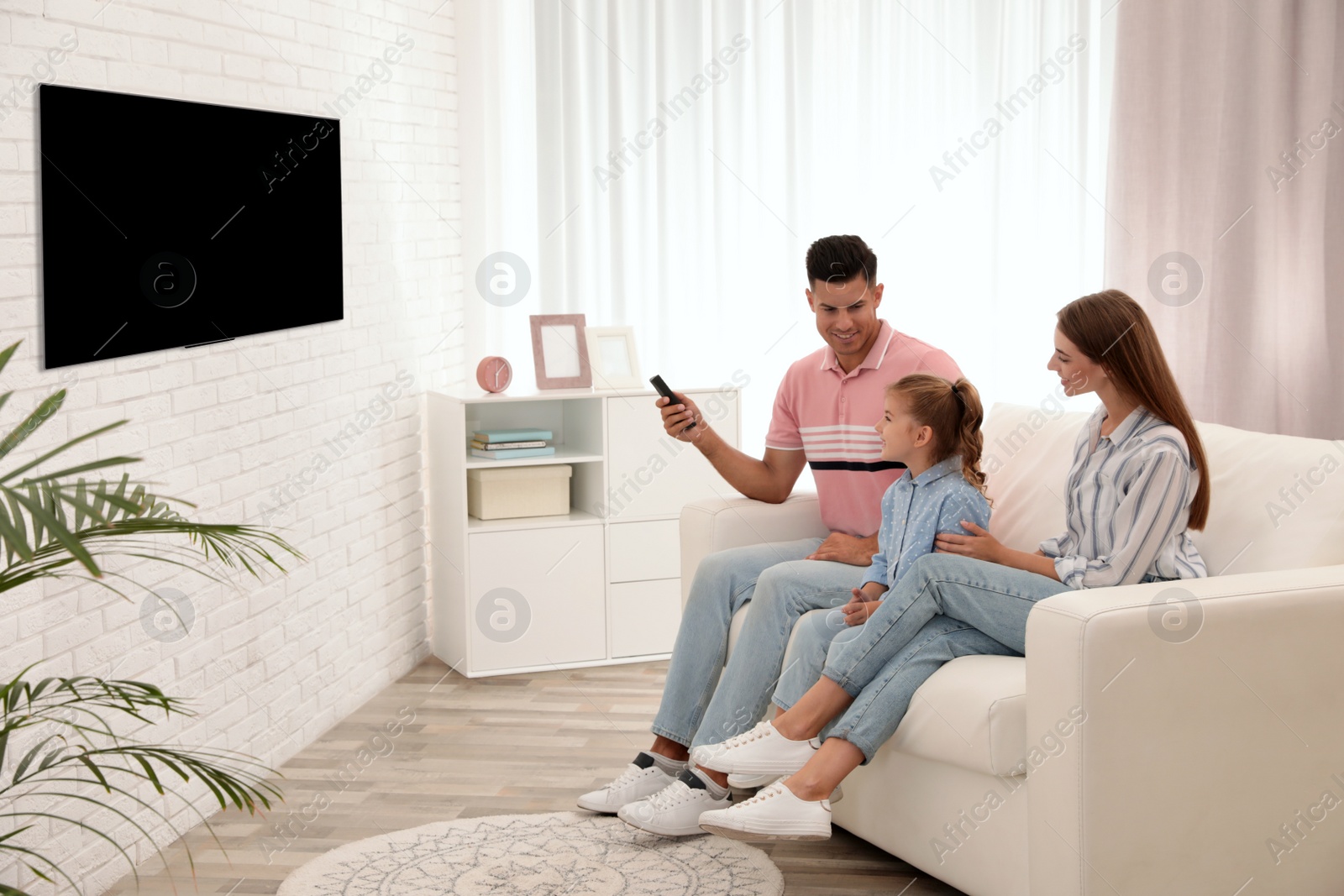 Photo of Happy family watching TV on sofa at home