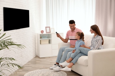 Happy family watching TV on sofa at home