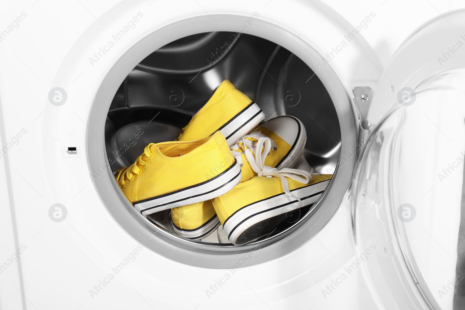 Photo of Stylish clean sneakers inside modern washing machine