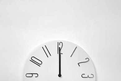 Photo of Stylish analog clock hanging on white wall, space for text
