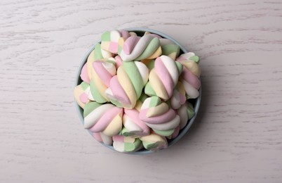 Photo of Bowl with colorful marshmallows on wooden table, top view