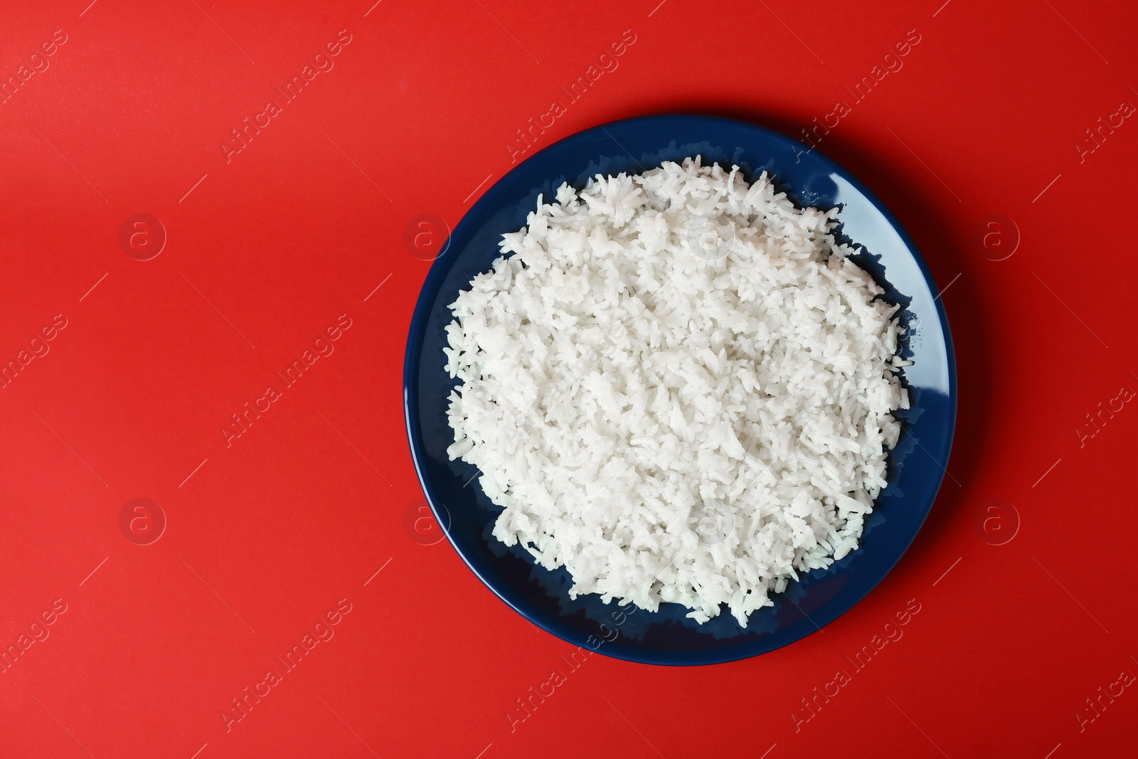 Photo of Plate of boiled rice on color background, top view with space for text