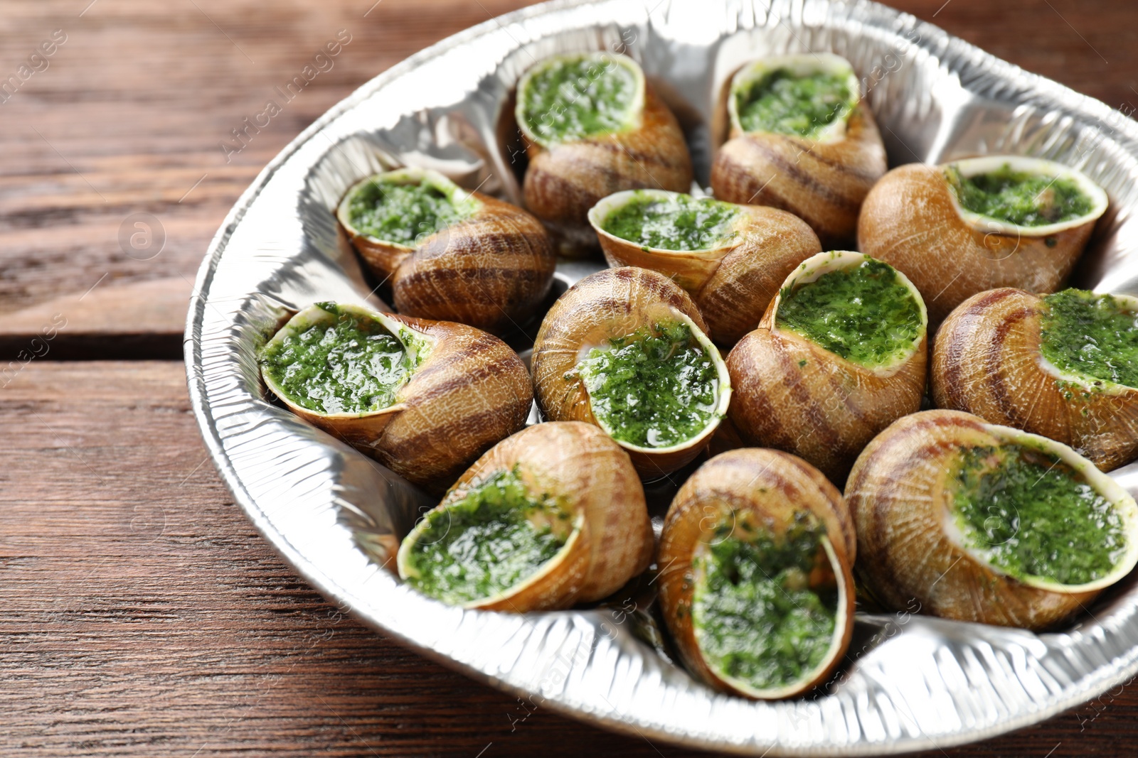 Photo of Delicious cooked snails on wooden table, closeup