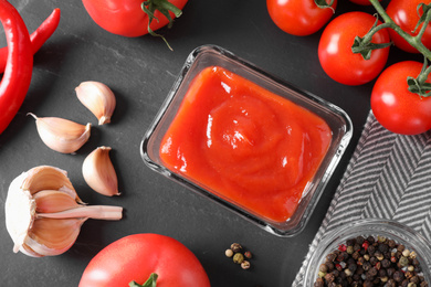 Flat lay composition with tomato sauce on black background