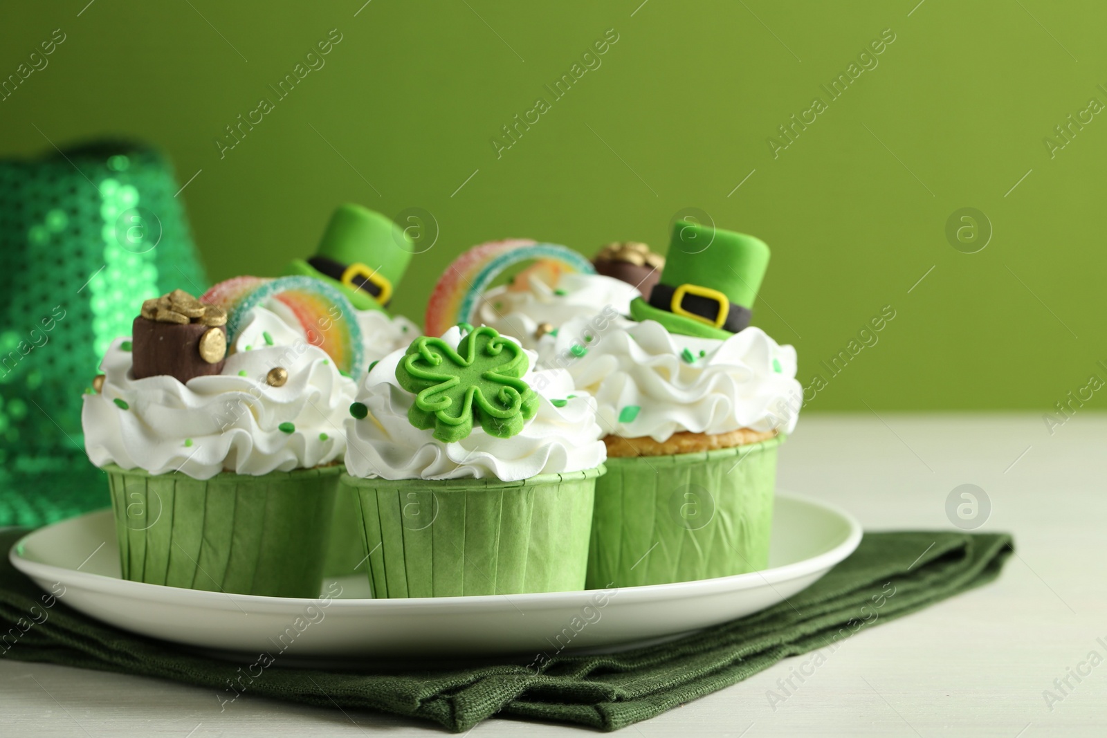 Photo of St. Patrick's day party. Tasty festively decorated cupcakes on white table, closeup