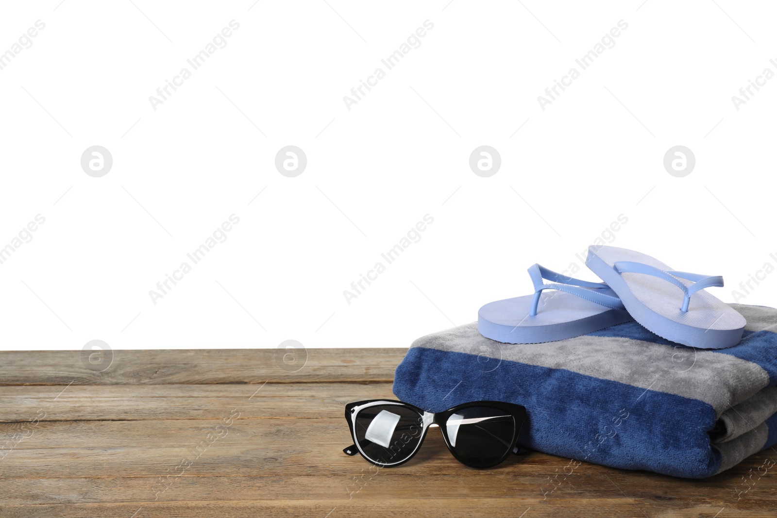 Photo of Beach towel, flip flops and sunglasses on wooden surface against white background. Space for text