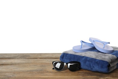 Beach towel, flip flops and sunglasses on wooden surface against white background. Space for text
