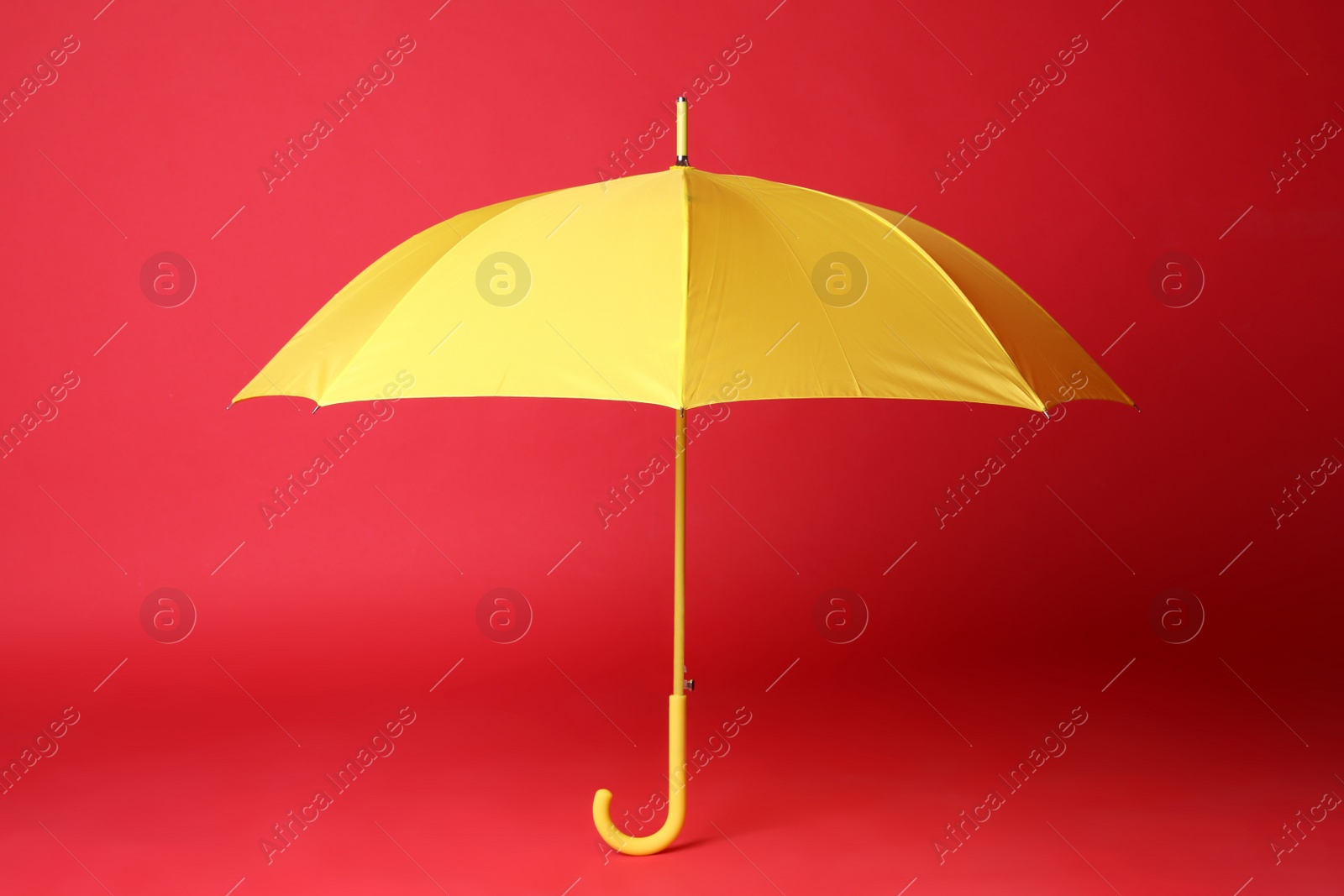 Photo of Stylish open yellow umbrella on red background