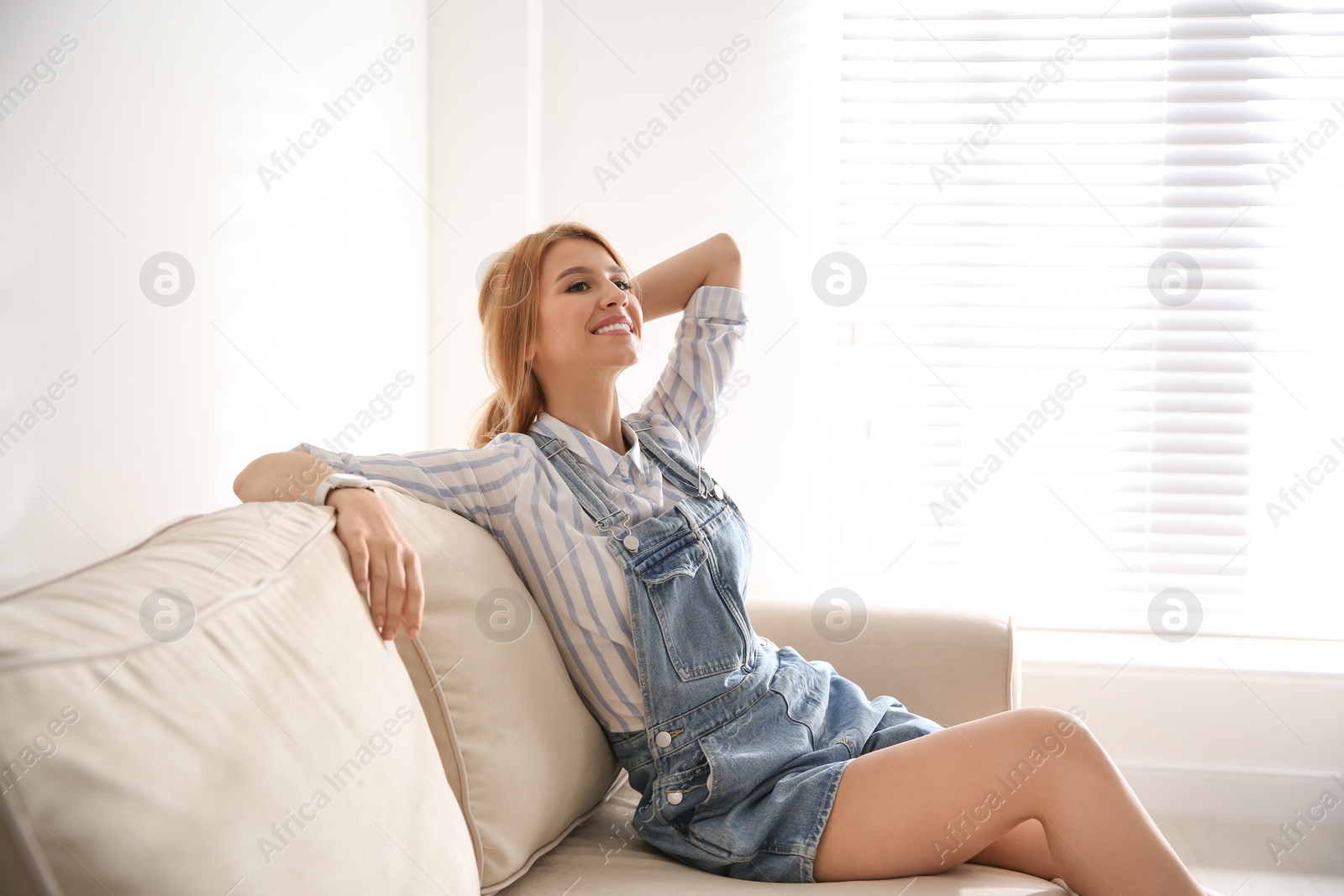 Photo of Young woman relaxing on couch near window at home