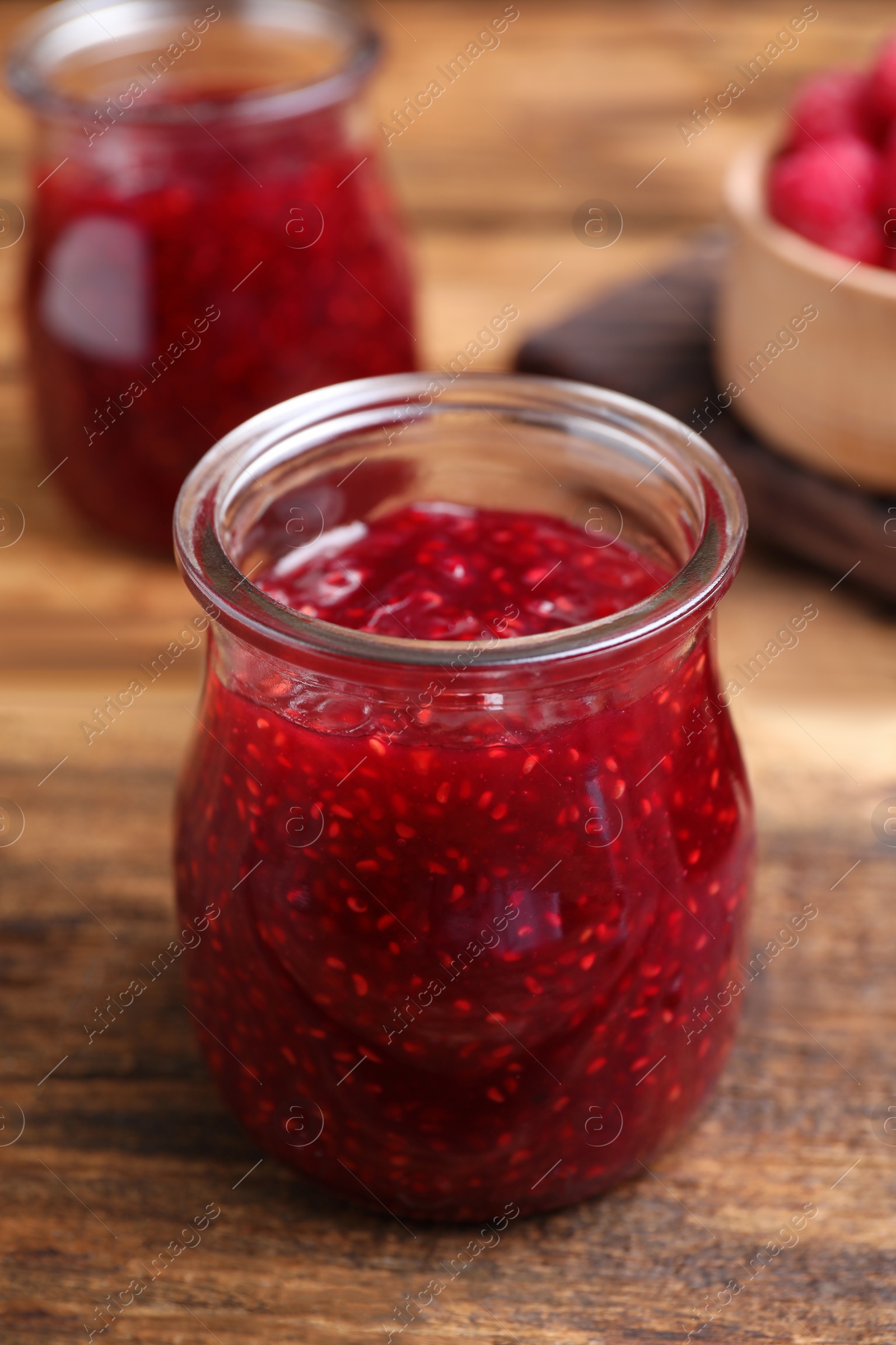 Photo of Delicious raspberry jam on wooden table, closeup