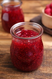 Delicious raspberry jam on wooden table, closeup