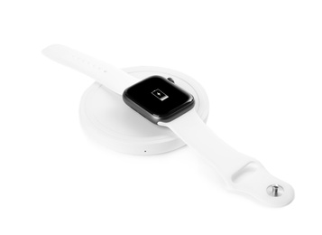Photo of Smartwatch charging with wireless pad isolated on white