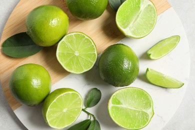 Photo of Fresh ripe limes and leaves on light table, top view
