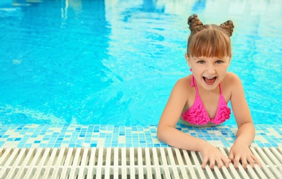 Happy girl resting in blue swimming pool