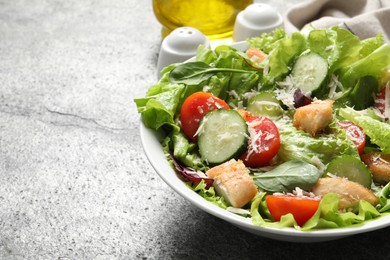 Photo of Delicious salad with chicken, cheese and vegetables on grey table, closeup. Space for text