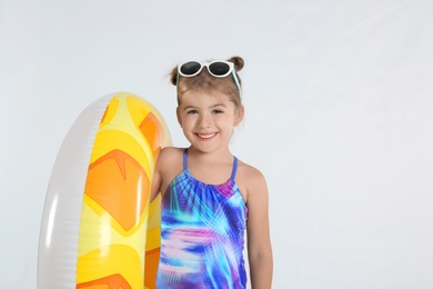 Cute little child in beachwear with bright inflatable ring on white background