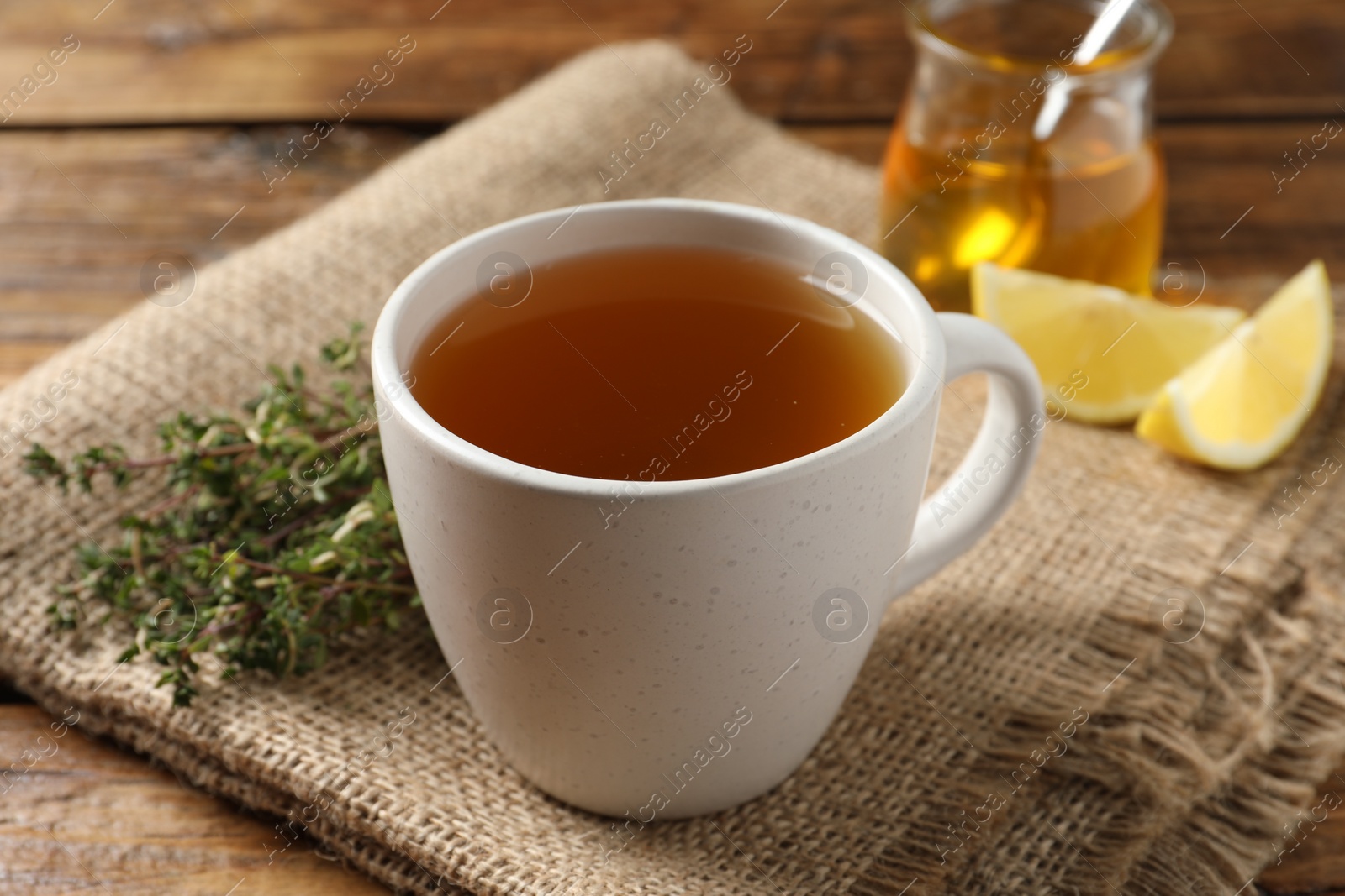 Photo of Aromatic herbal tea with thyme on wooden table, closeup