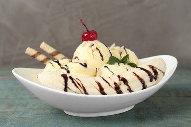 Photo of Delicious dessert with banana ice cream on light blue wooden table