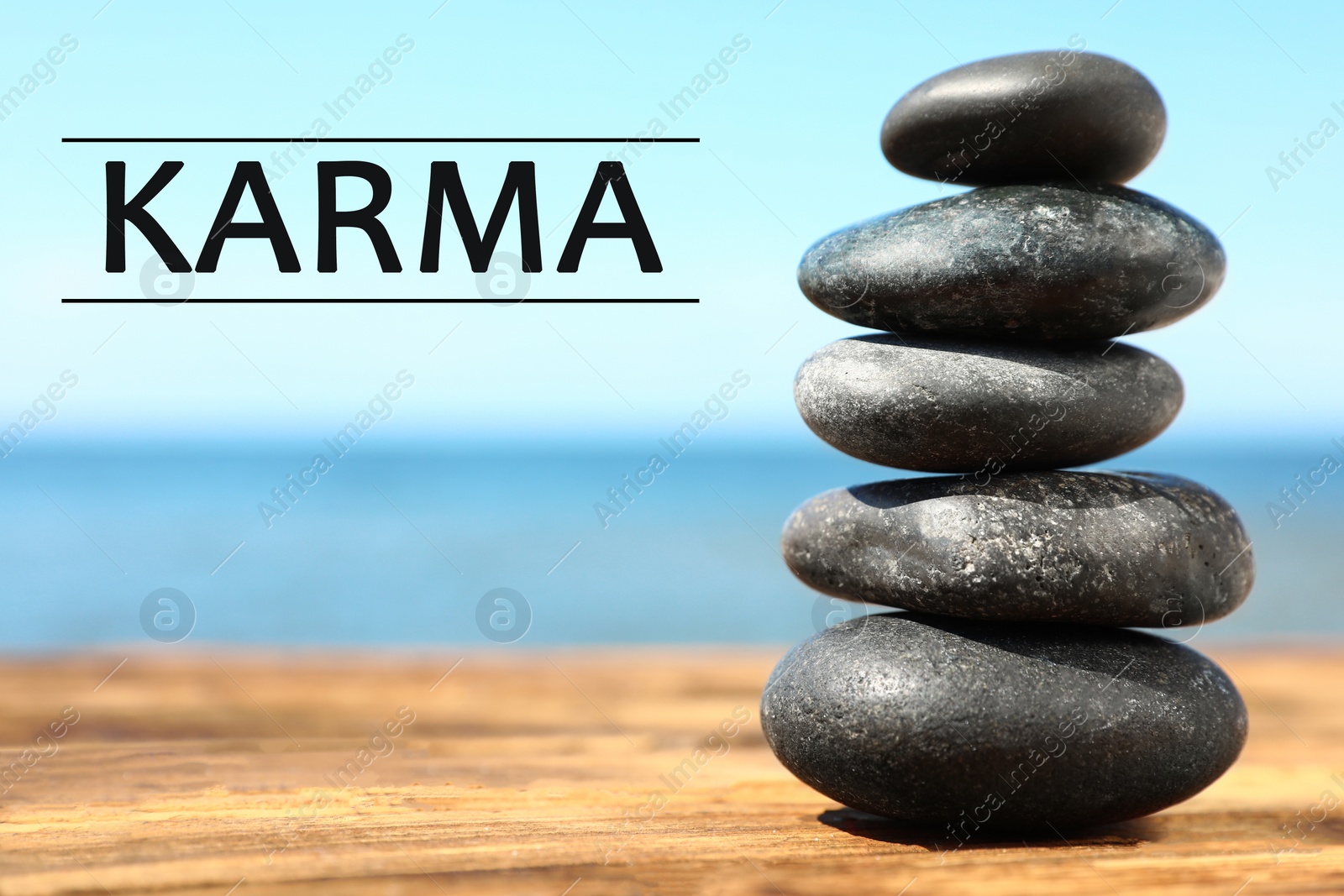 Image of Karma concept. Stack of stones on wooden surface against seascape