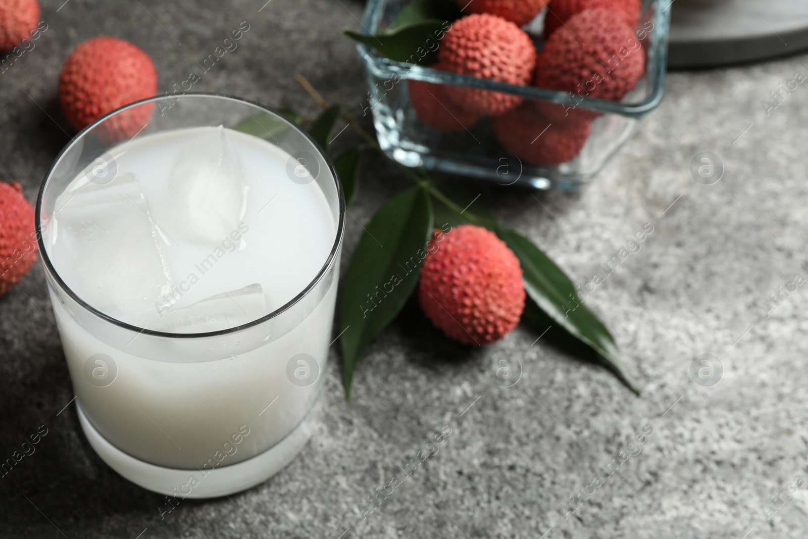 Photo of Glass with fresh lychee juice on grey table