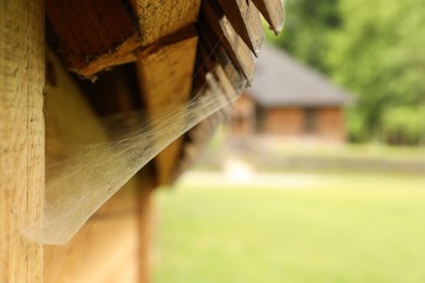 Photo of Cobweb on wooden building outdoors, closeup. Space for text