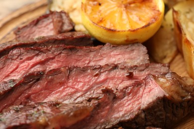Delicious grilled beef with potato and lemon on table, closeup