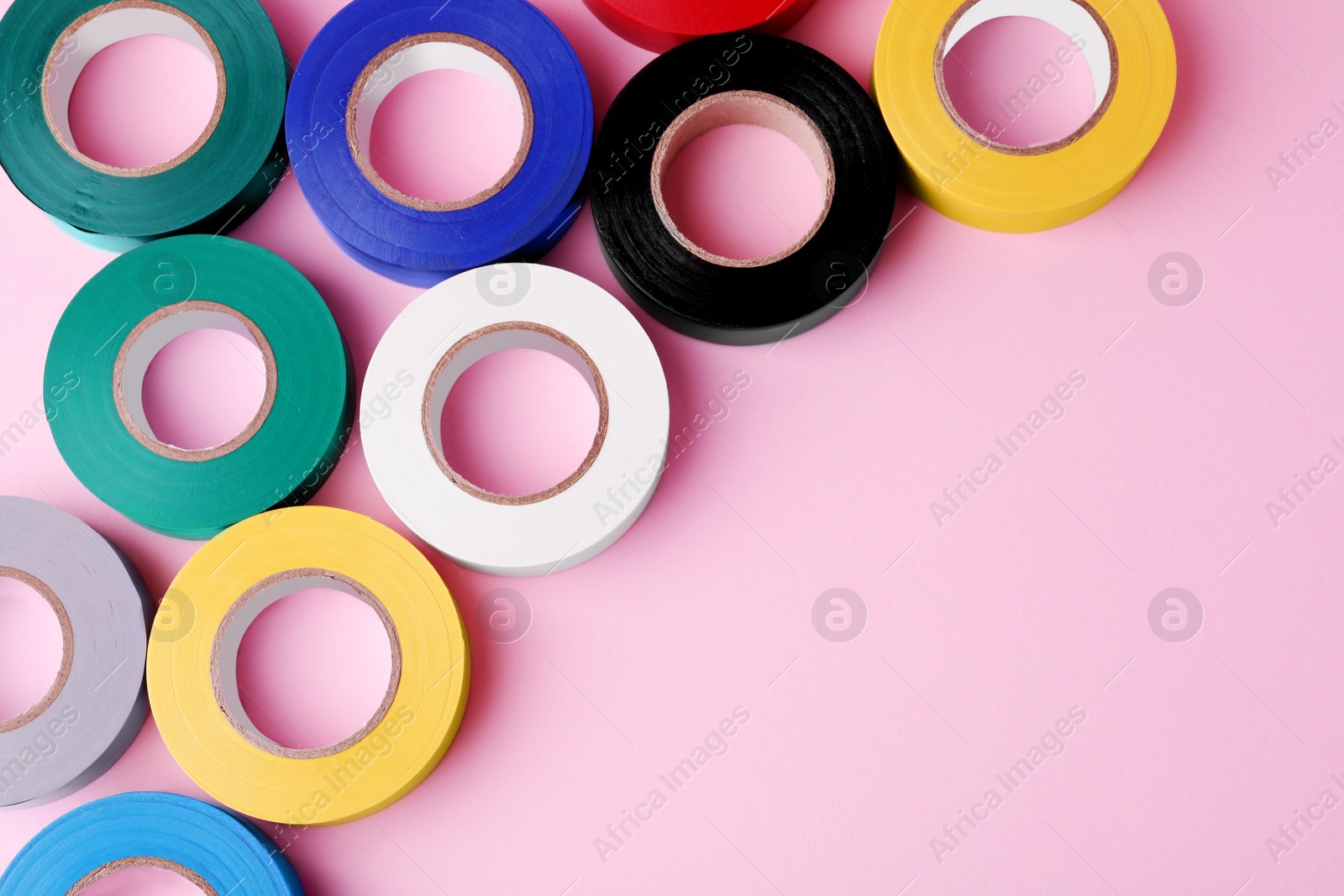 Photo of Colorful insulating tapes on pink background, flat lay. Space for text