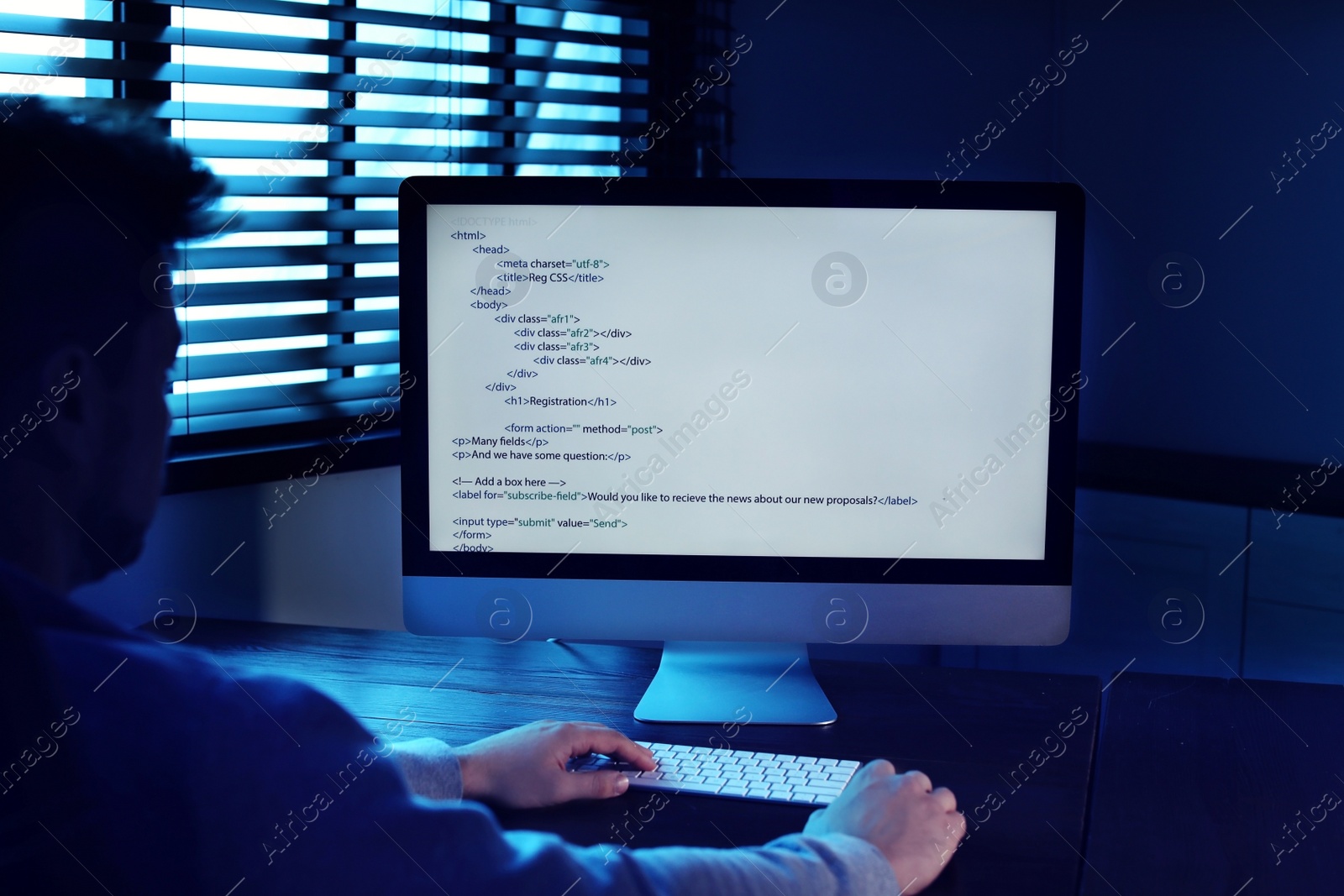 Photo of Man using computer in dark room. Criminal offence