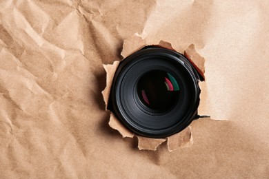 Photo of Hidden camera lens through torn in paper. Space for text