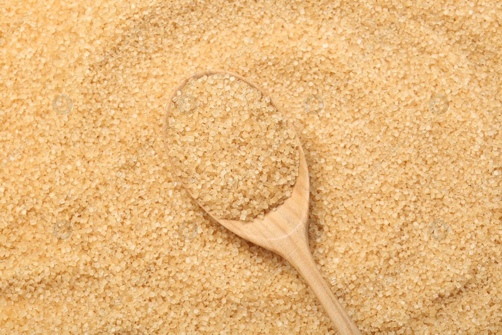 Photo of Spoon on granulated brown sugar, top view