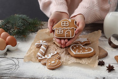 Photo of Woman holding delicious homemade Christmas cookie at wooden table, closeup