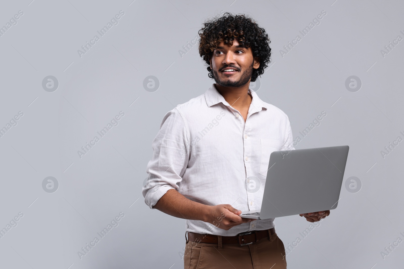 Photo of Smiling man with laptop on light grey background, space for text