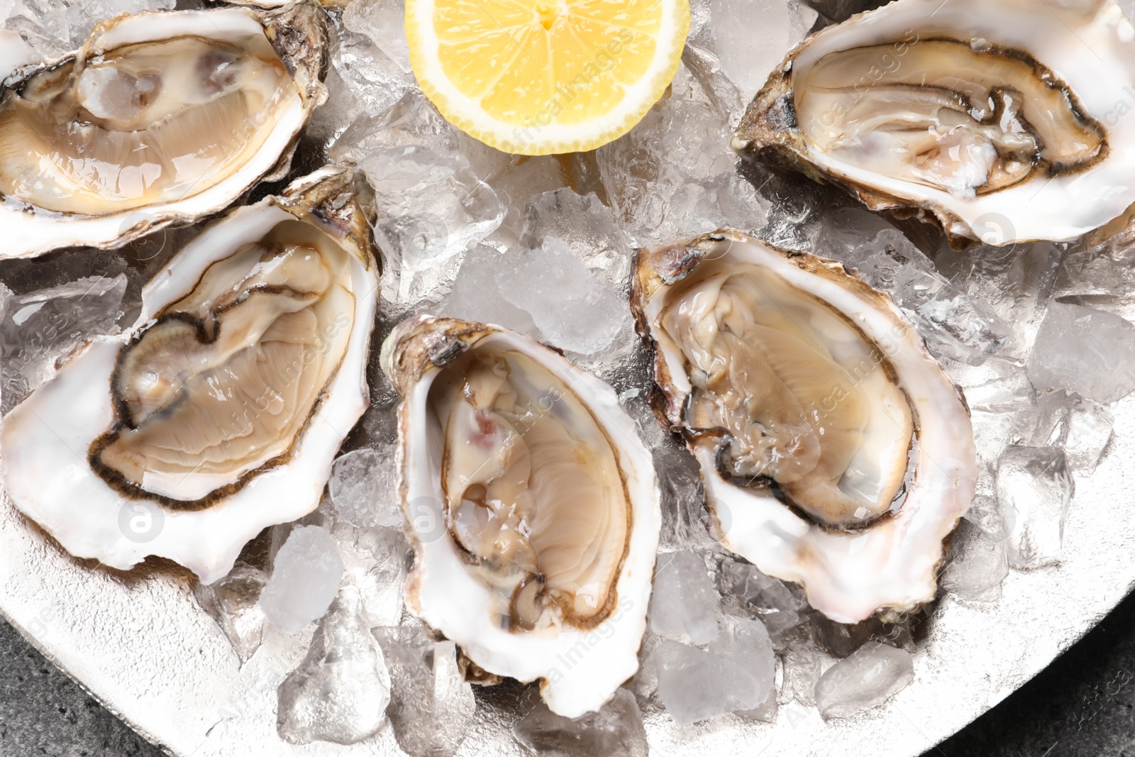 Photo of Delicious fresh oysters with lemon and ice on table, top view