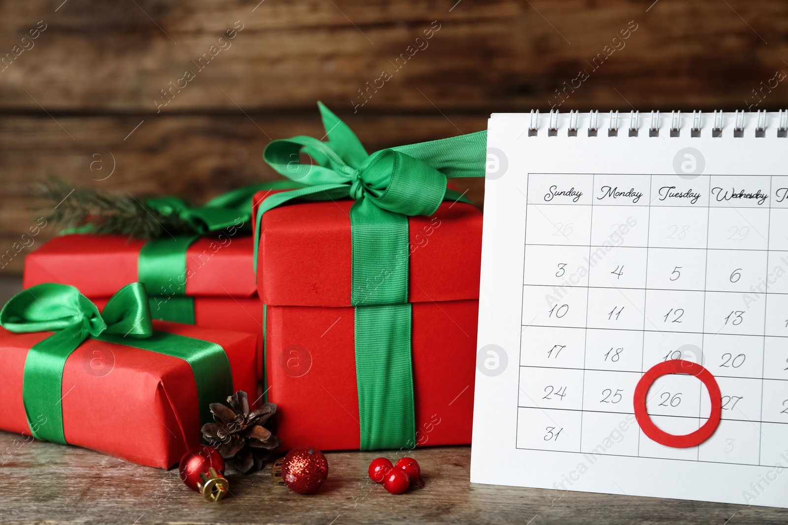 Photo of Calendar with marked Boxing Day date near gifts on wooden table