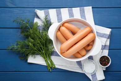 Photo of Bowl of delicious sausages, dill, pepper and salt on blue wooden table, flat lay