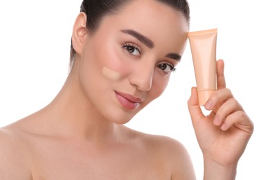 Woman holding tube of foundation on white background