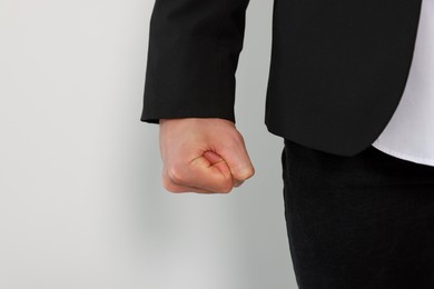 Photo of Young man showing fist on white background, closeup. Aggression concept