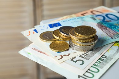 Photo of Euro banknotes and coins on blurred background, closeup