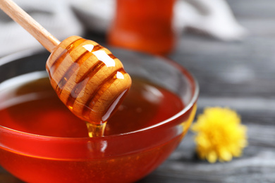 Glass bowl with organic honey and dipper, closeup