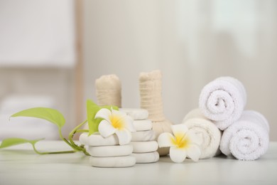 Composition with different spa products and plumeria flowers on white marble table indoors