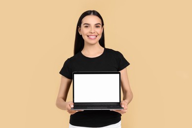 Photo of Happy woman with laptop on beige background