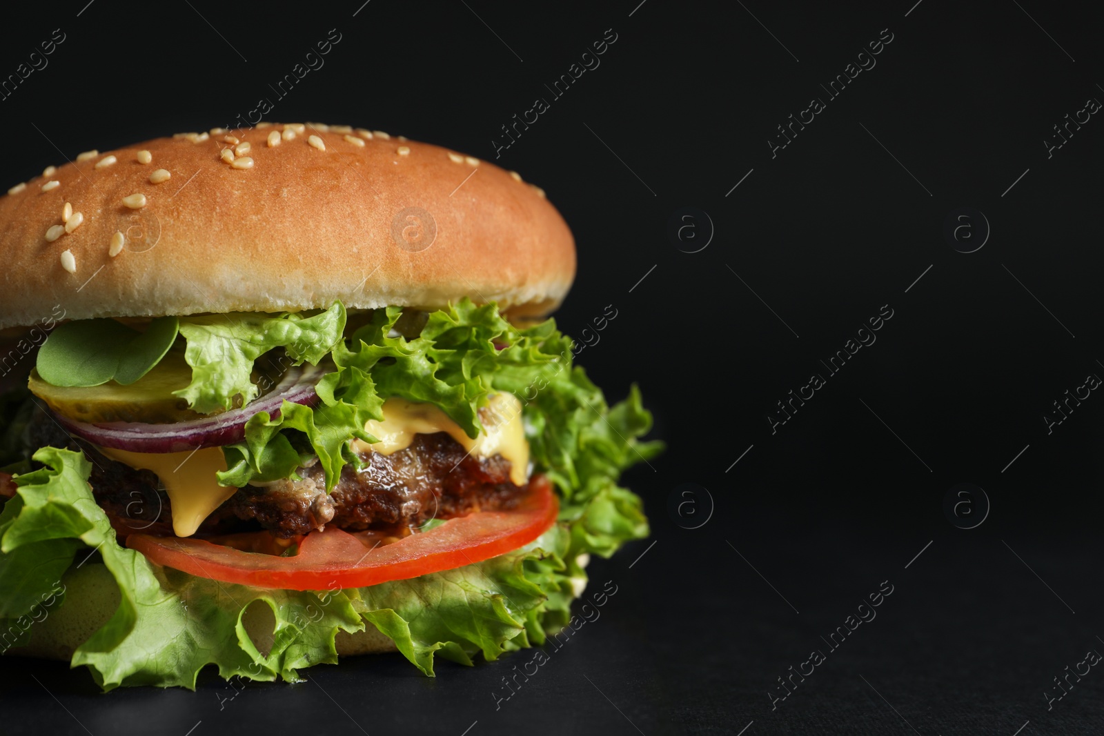 Photo of Delicious burger with beef patty and lettuce on black background, closeup. Space for text