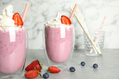 Tasty milk shakes with fresh berries on grey marble table