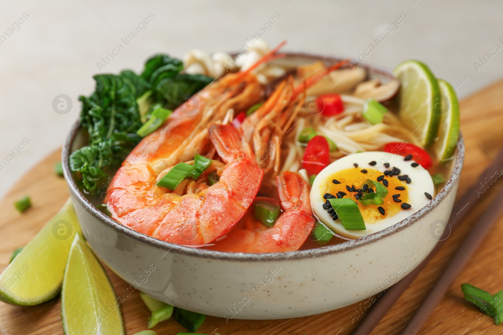 Photo of Delicious ramen with shrimps and egg in bowl on table, closeup. Noodle soup